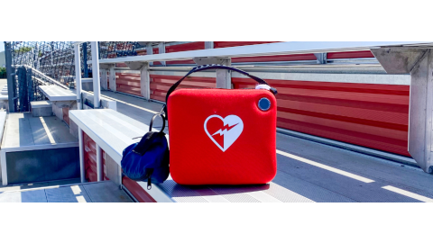 An AED box sitting on outdoor bleachers
