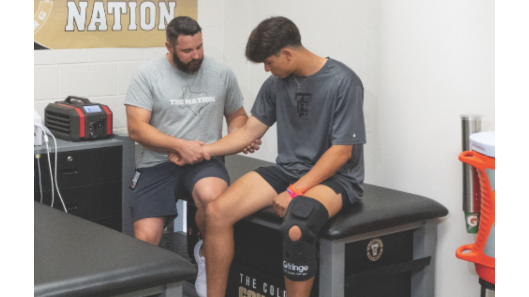 An athletic trainer assists and athlete on a treatment table