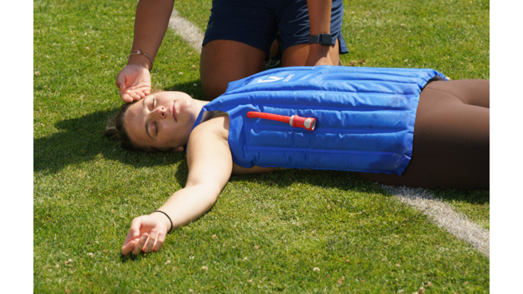 A female athlete lays on the ground with the ColdVest on, recovering from heatstroke