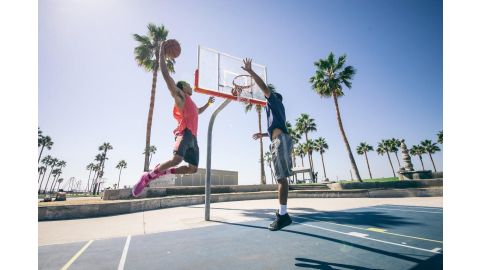 person with basketball jumping for a slam dunk